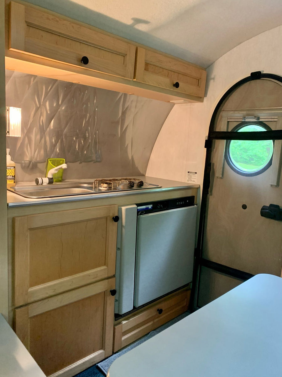 ready for adventure.|Vibrant green & white teardrop **RV rental** set for camping in a lush forest