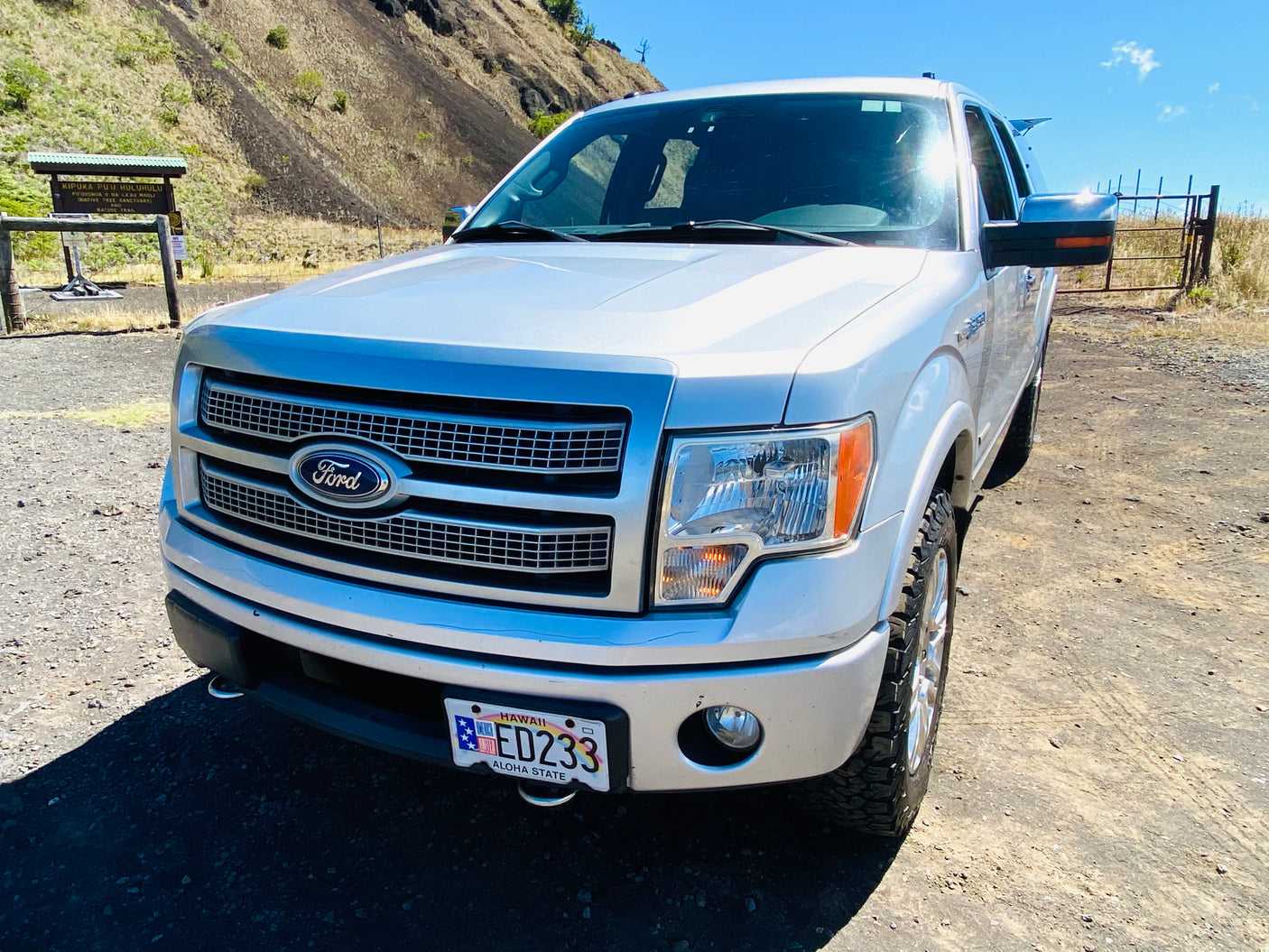 A silver Ford F-150 pickup truck parked near a Hawaiian nature trail. A great heavy-duty rv rental alternative for island exploration.