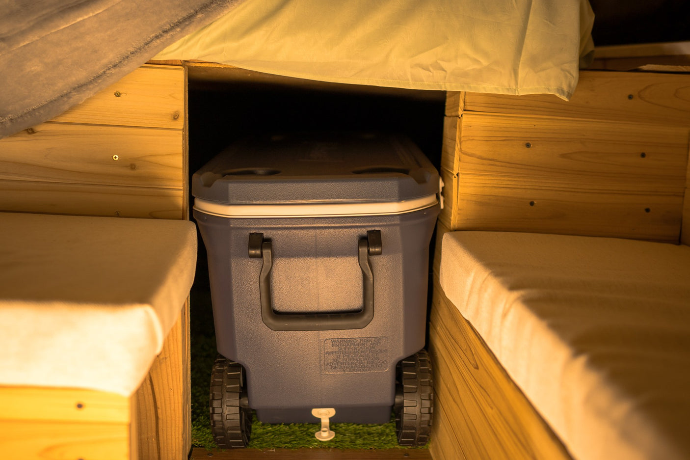 RV rental: Spacious cooler with wheels fits perfectly in camper's custom wooden bed frame/bench setup.