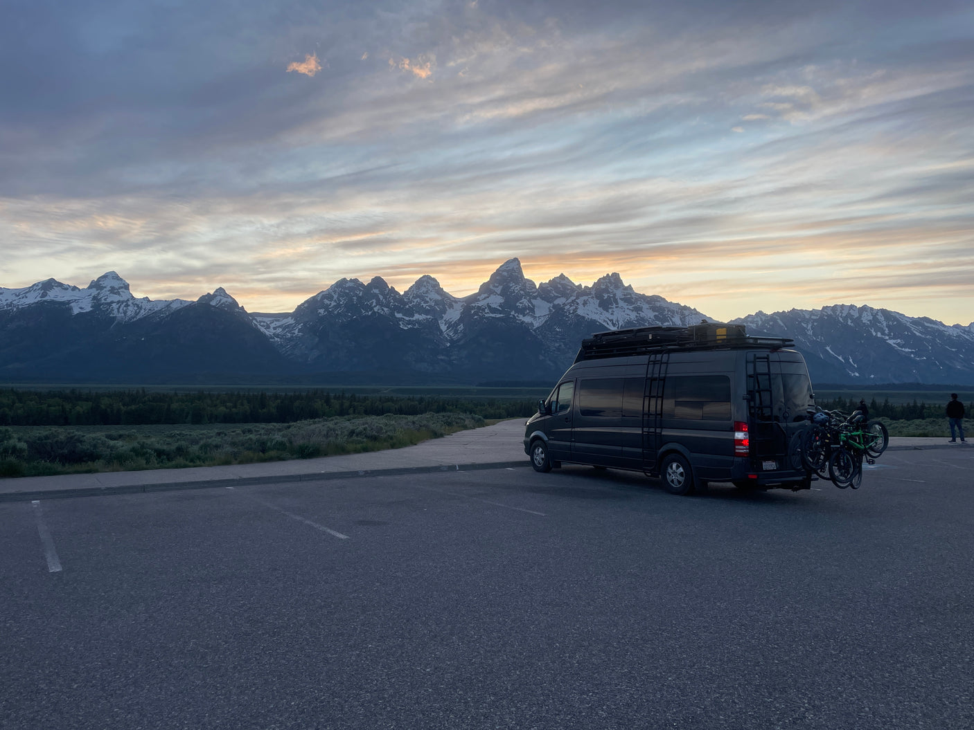 Grand Teton mountains & landscape at sunset/sunrise with an RV rental camper van, bikes on back.