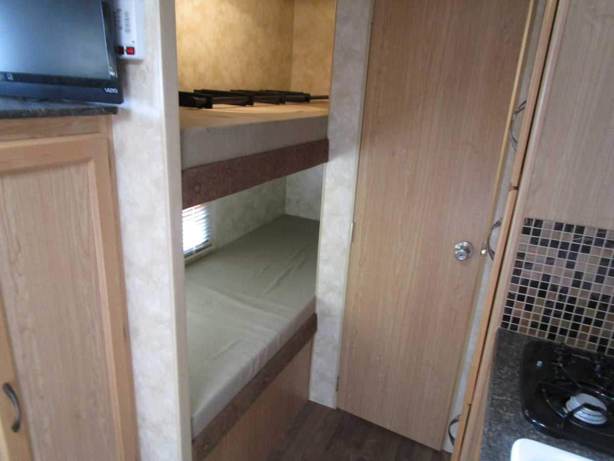 Interior view of an RV rental featuring cozy bunk beds, a TV area, and a compact kitchen space. — photo 7