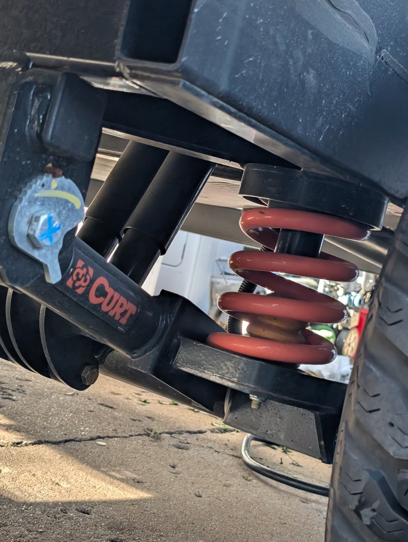 Detailed view of an RV rental's suspension, featuring a red coil spring, black shock absorbers, and CURT frame components.