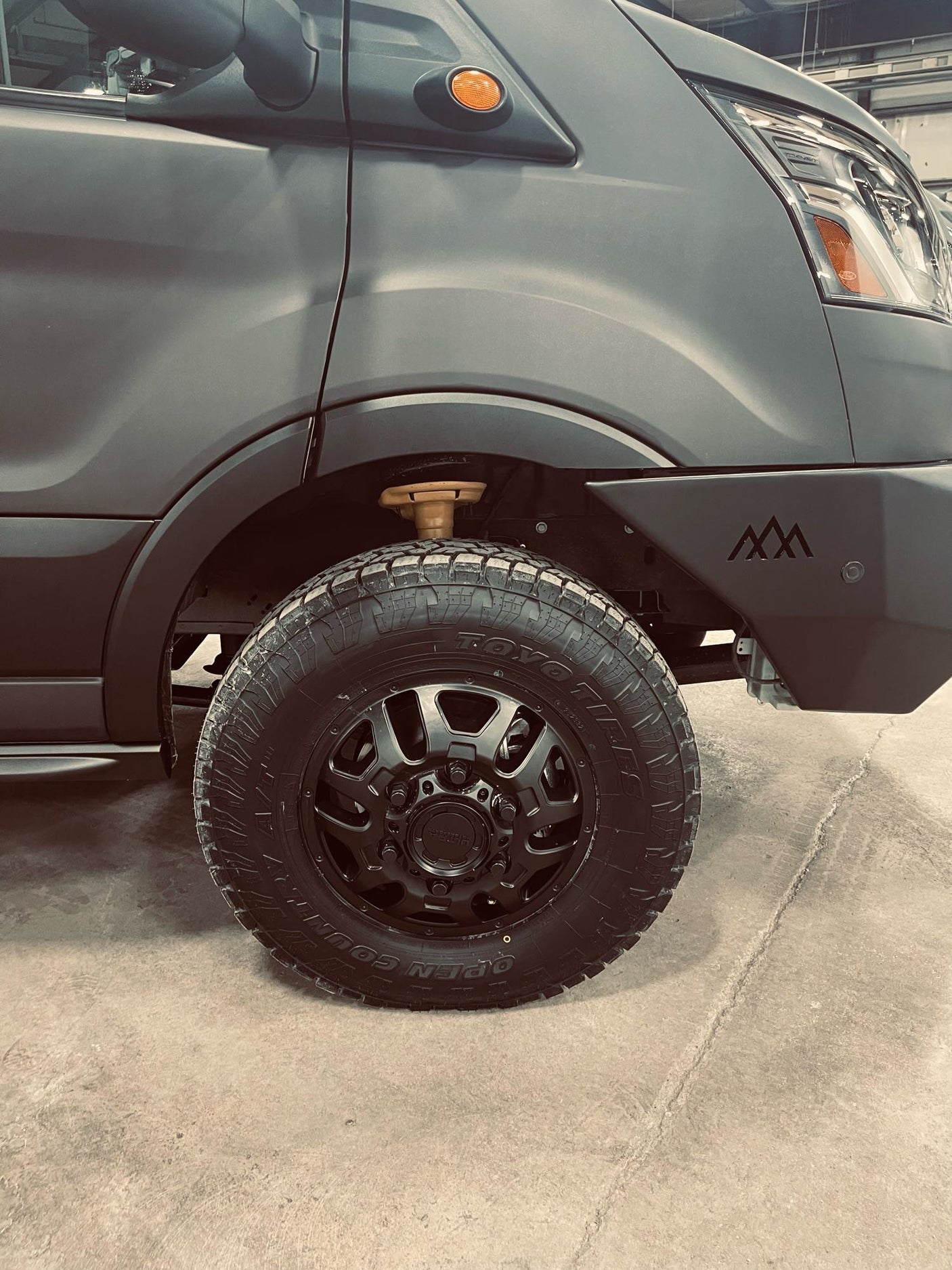 parked on a sunny city street with urban buildings.|A dark grey **vondewit RV rental** van parked at **The National Hotel** and **Second Chance Bakery**. Great **camper van** for **travel** in a **historic mountain town**.|Custom dark gray Ford Transit adventure van