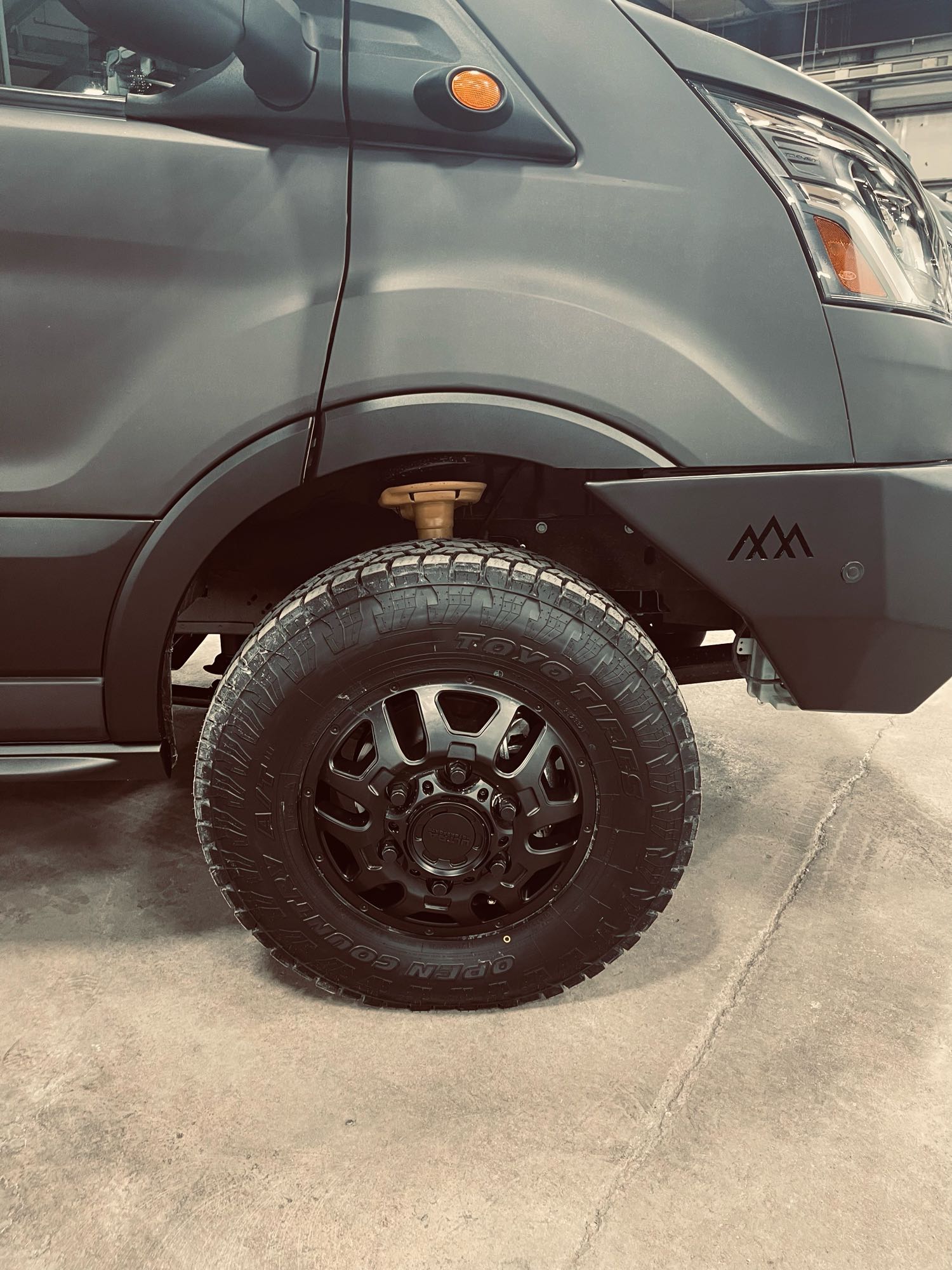 parked on a sunny city street with urban buildings.|A dark grey **vondewit RV rental** van parked at **The National Hotel** and **Second Chance Bakery**. Great **camper van** for **travel** in a **historic mountain town**.|Custom dark gray Ford Transit adventure van
