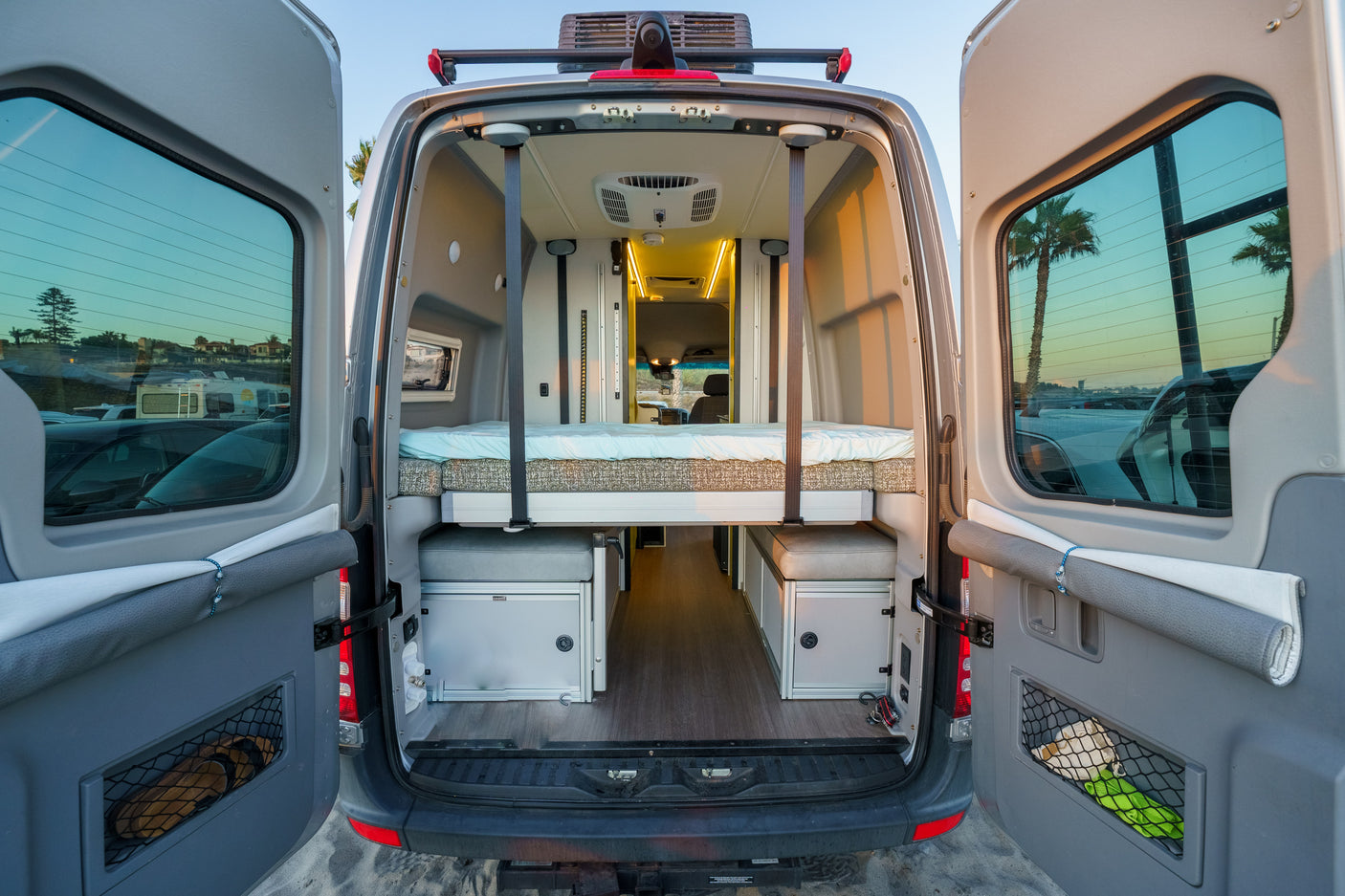 Step into comfort: this RV rental reveals its spacious camper van interior with an elevated bed, ample storage & scenic views.