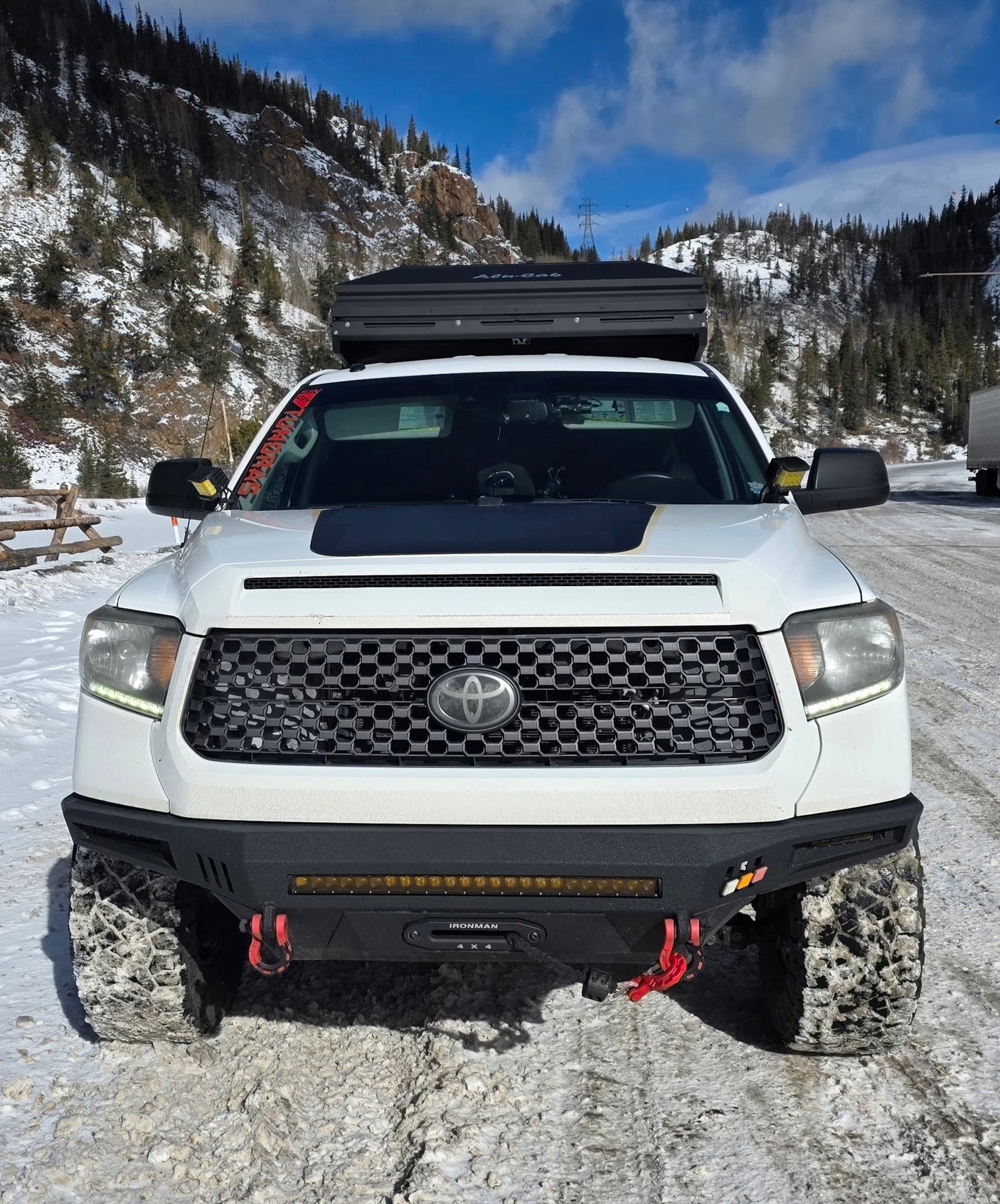 This off-road Toyota Tundra with a roof top tent in a snowy mountain landscape offers a unique adventure alternative to an rv rental.