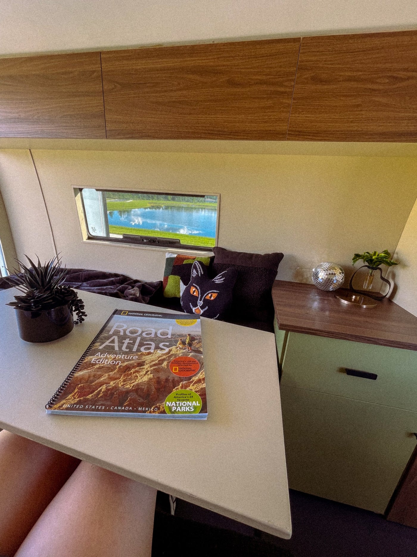 Cozy rv rental interior featuring a National Geographic Road Atlas. Planning adventures with a lake view outside and comfy decor. — photo 4