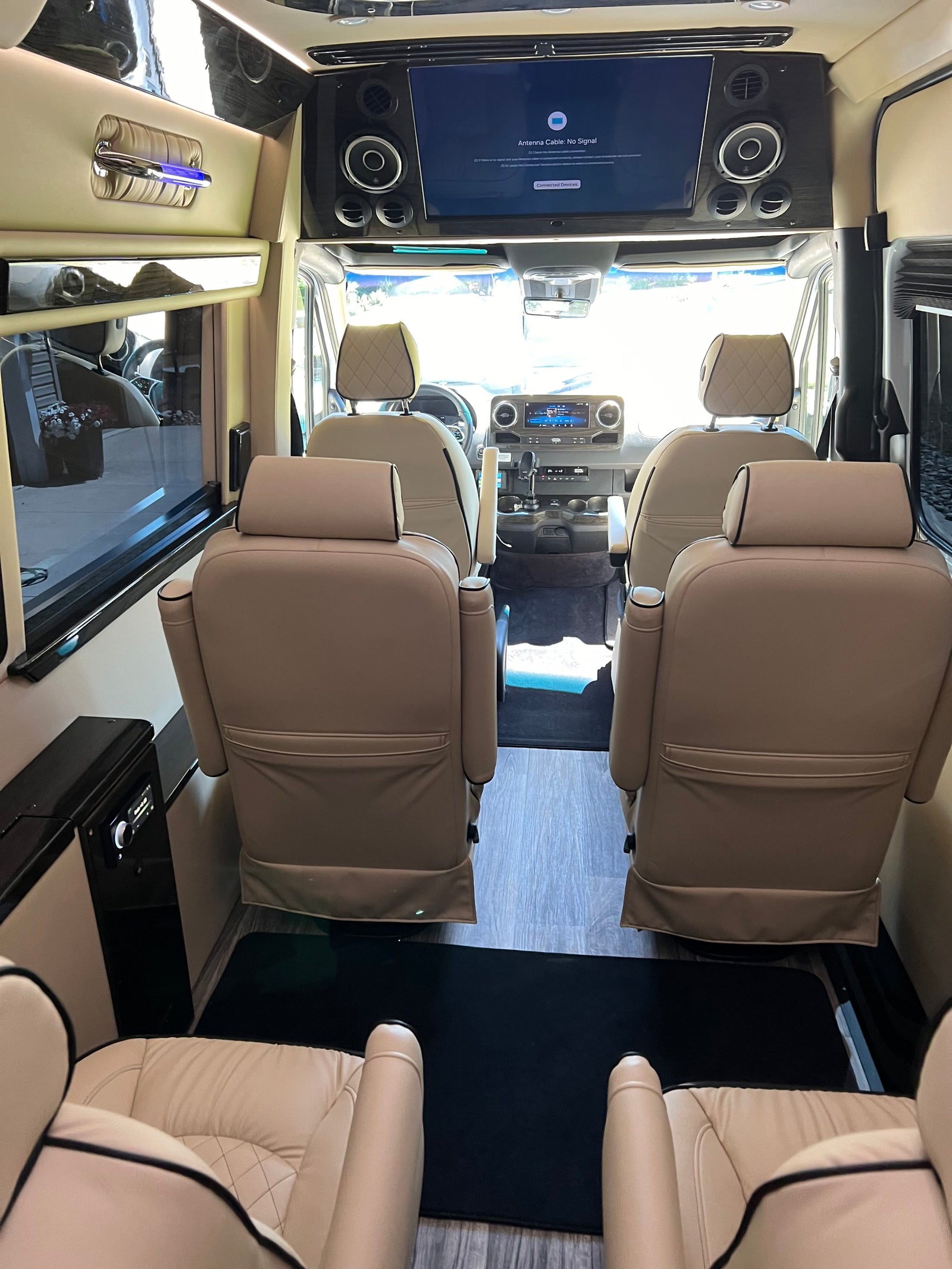 Luxury RV rental interior: tan leather captain's chairs, large screen, plush comfort for travel.