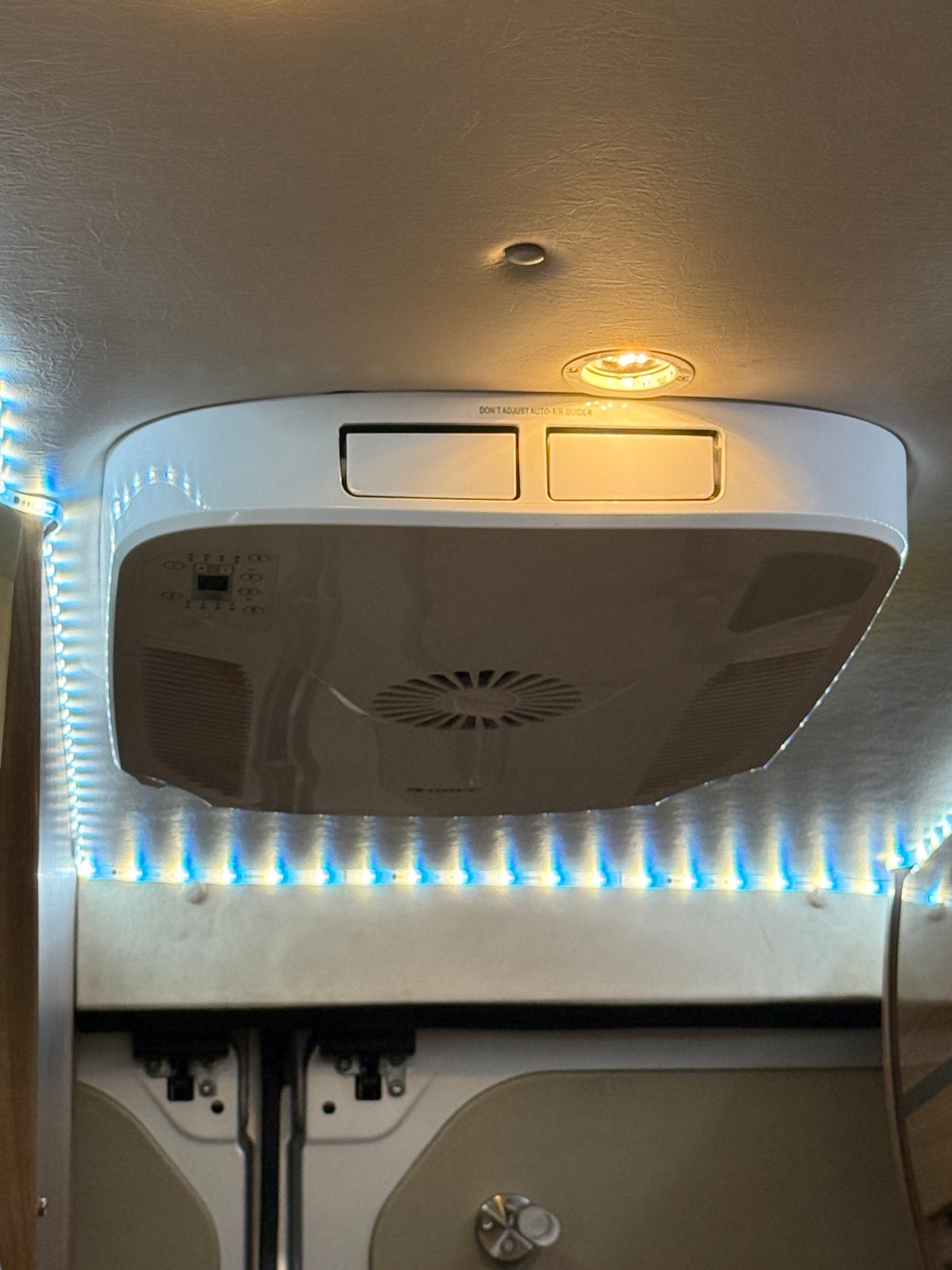 An RV rental's ceiling-mounted AC unit and vibrant LED strip lights provide climate control and bright ambiance.