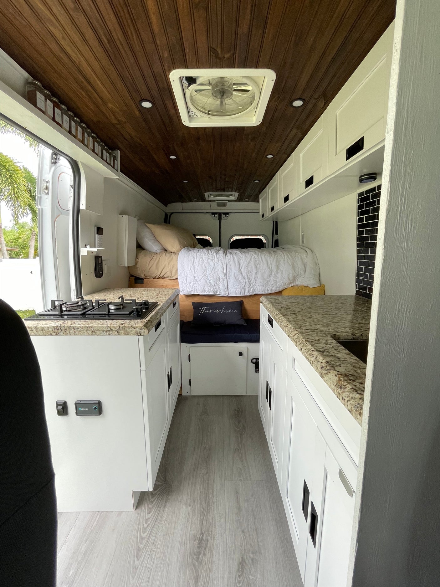 This rv rental's spacious interior features a full kitchen with granite counters, a cozy bed, and warm wood ceilings.