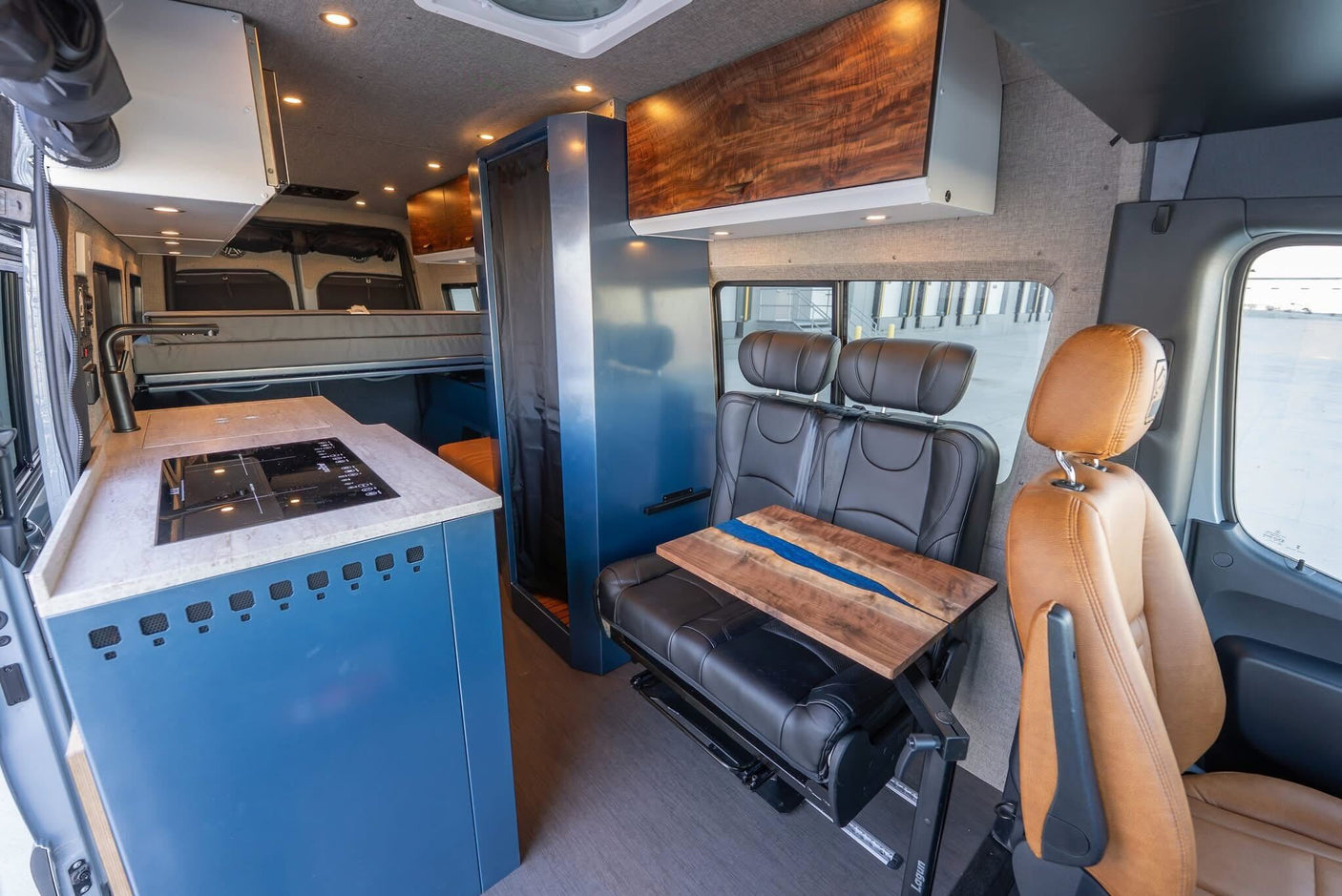 Luxury rv rental interior: modern kitchen, fold-down bed, and unique river-style dining table for comfortable travel.