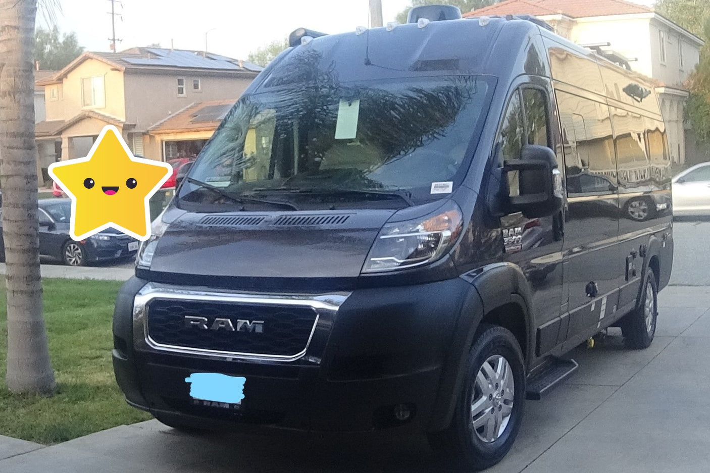A dark gray Ram ProMaster camper van, an RV rental, parked on a suburban driveway.