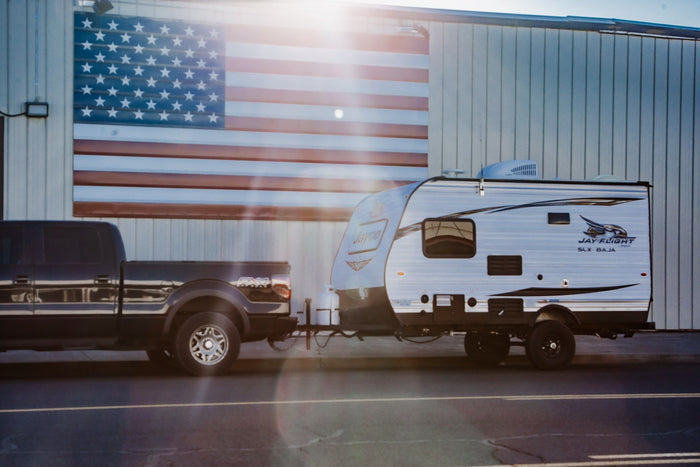 & log seats.|Enjoy an RV rental: a travel trailer parked riverside with awning & lights for a peaceful evening camp in nature.|Enjoy a scenic RV rental adventure! This travel trailer is set up with a truck