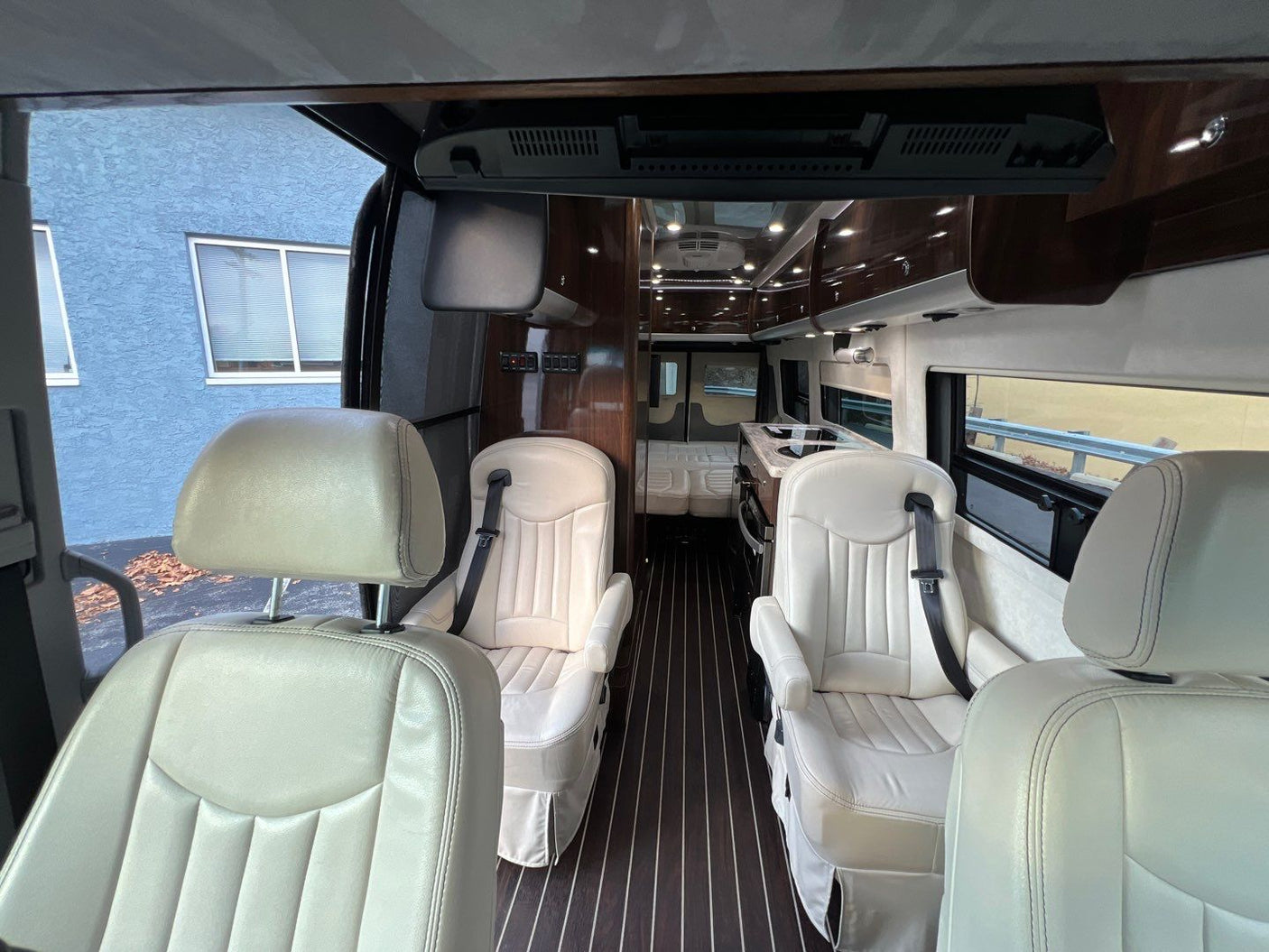 and large windows for scenic rides.|Silver Airstream RV rental parked with its gray awning extended above the open side door.|RV rental: Luxurious van interior with cream leather seating