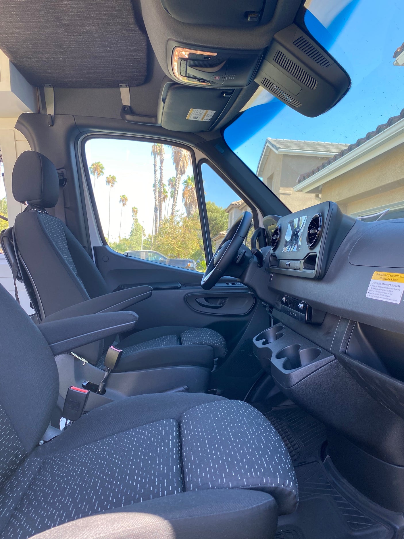 RV rental's front cabin: comfortable driver and passenger seats, dashboard, and steering wheel are visible, ready for your journey.