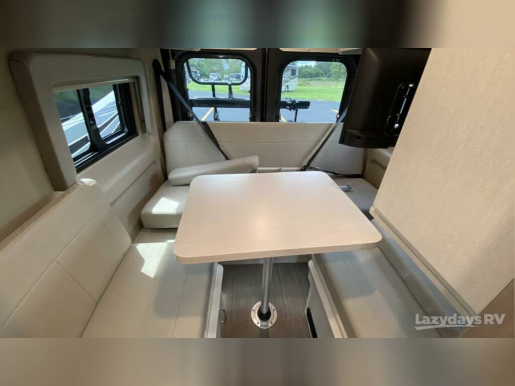 RV rental interior: dinette with light-colored padded benches, table, and large windows for scenic views.