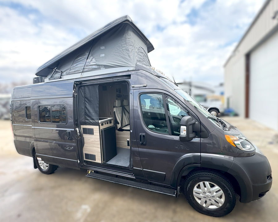 Dark gray pop-top camper van, side door open to interior amenities. Ideal for your next rv rental.
