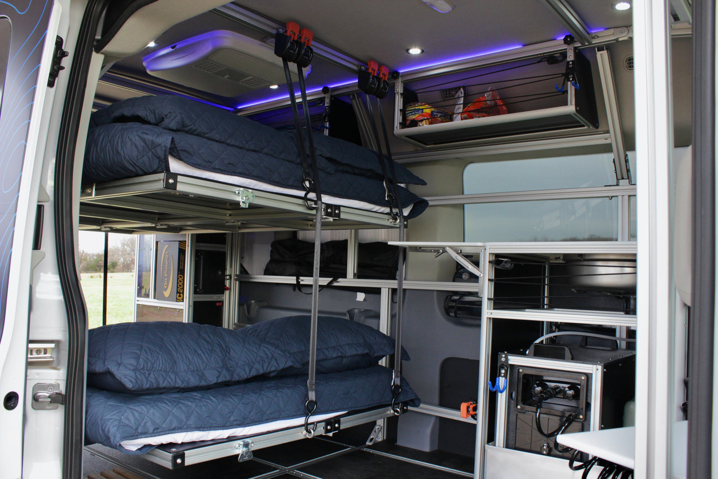 Modular RV rental interior featuring suspended bunk beds, smart storage, and integrated power for travel comfort.