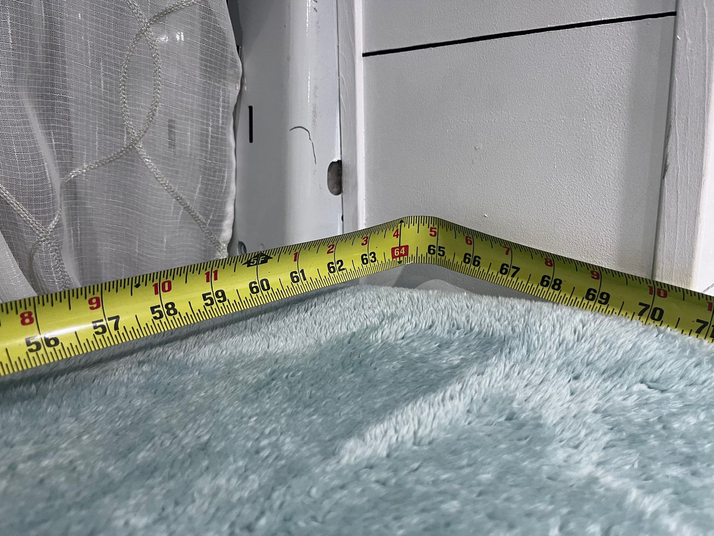 RV rental interior measurement: tape measure shows ~56-70 inches across plush blue fabric, likely a bed or seating area.