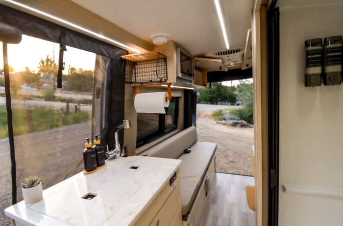 parked against a stunning backdrop of snow-capped mountains.|Bright RV rental interior with a modern kitchenette