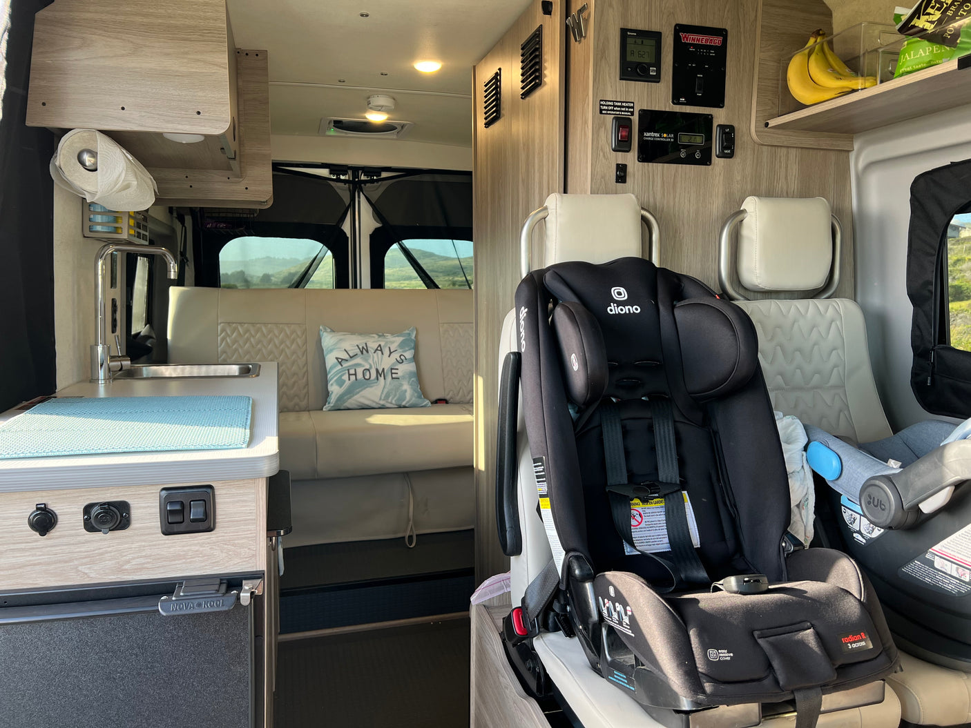 Family-friendly RV rental interior with kitchenette, seating, and child car seats for comfortable road trips.