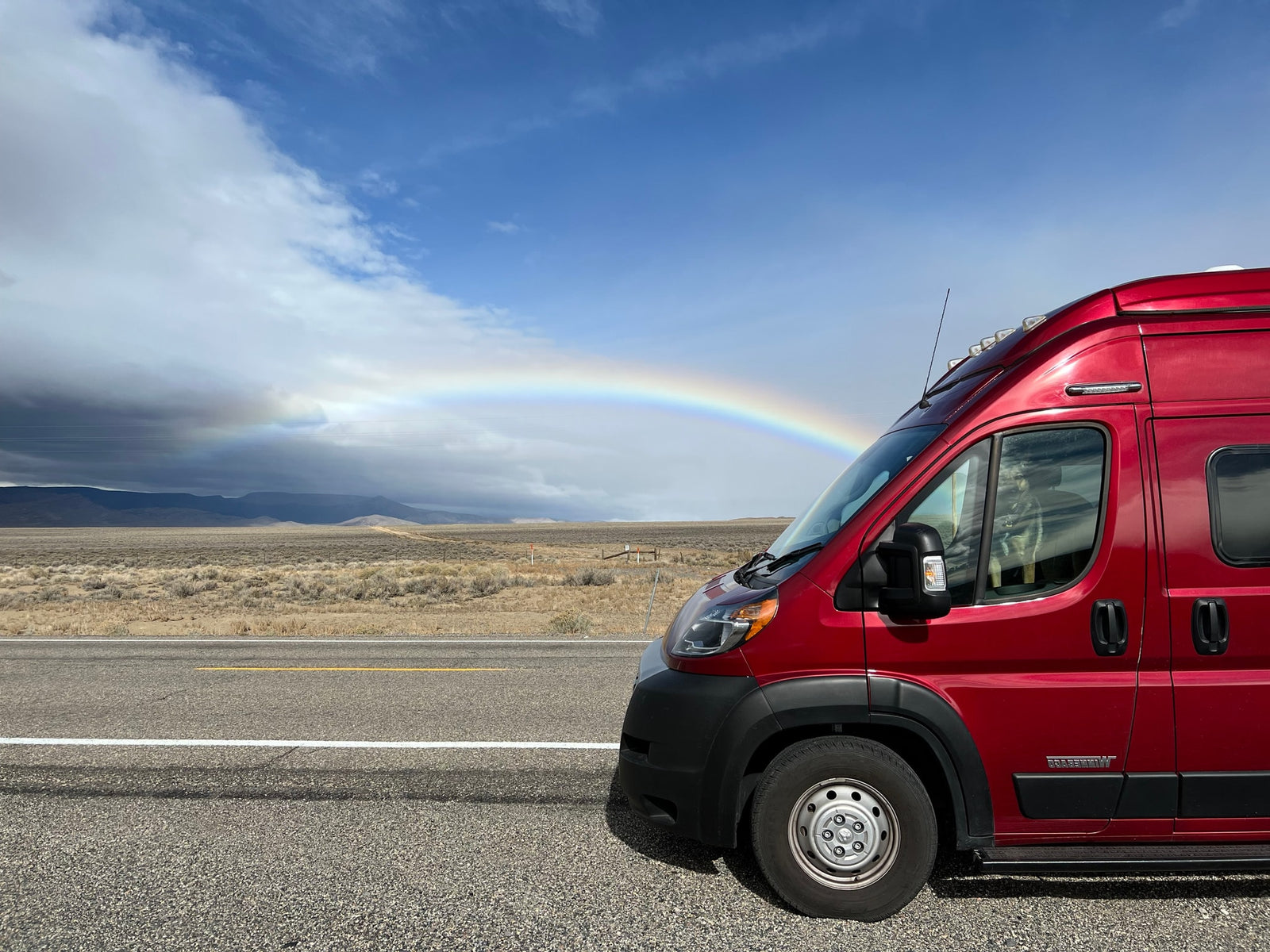 Red camper van (RV rental) on a scenic road trip