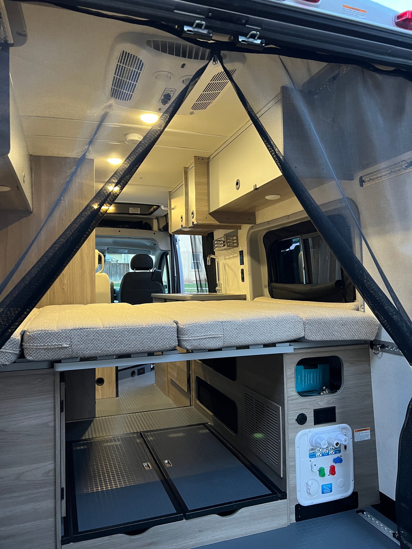 RV rental interior: A compact camper van with a rear bed, kitchen, ample storage, and a magnetic bug screen.