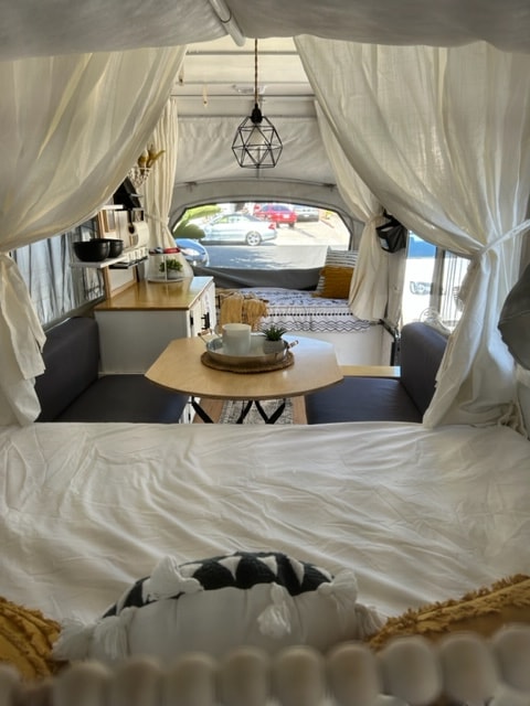 Bright, cozy RV rental interior: white bed linens, geometric lamp, and seating area for your next adventure. — photo 12
