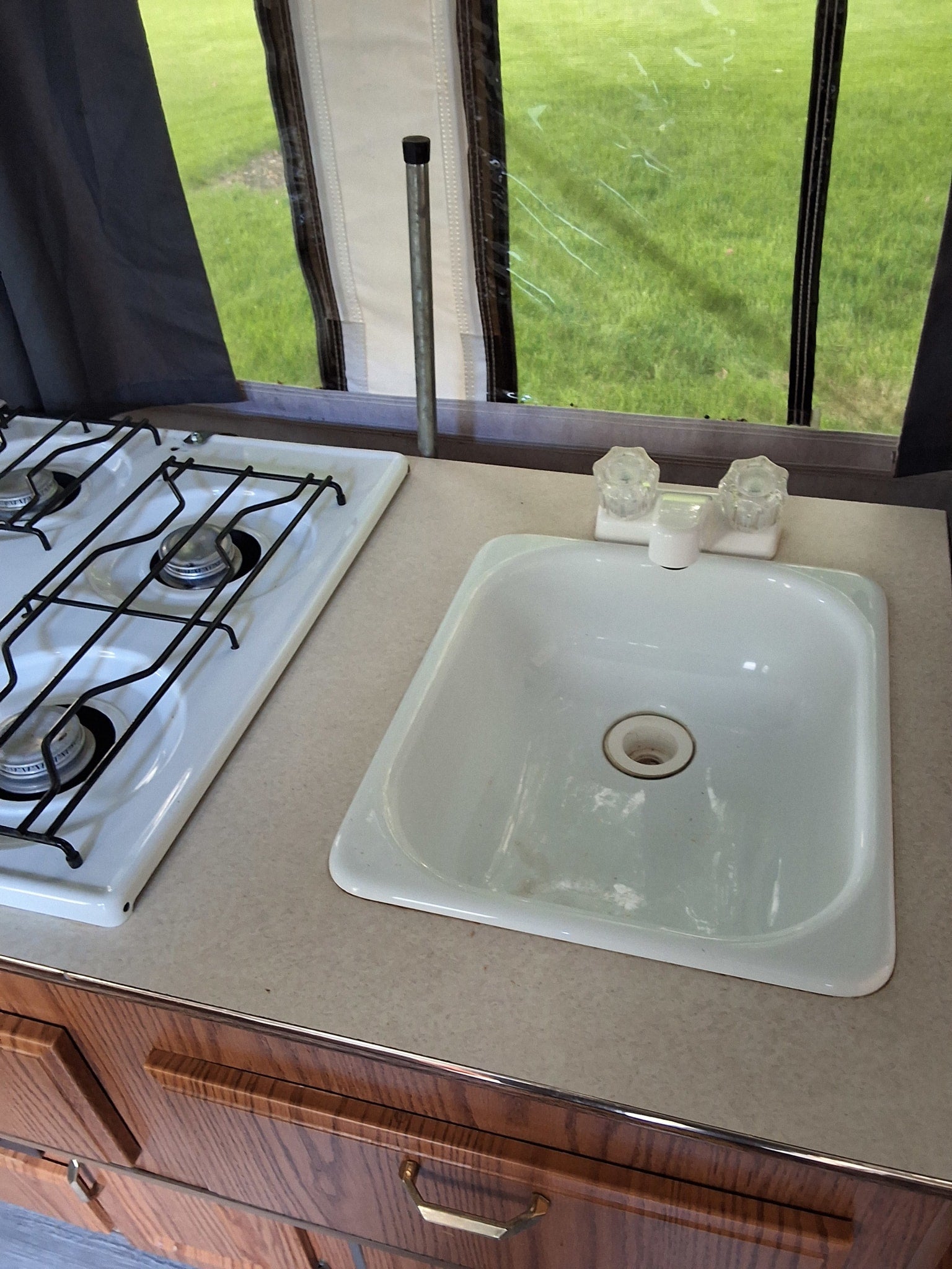 This RV rental's small kitchenette features a two-burner stove, sink, and wood cabinets, perfect for road trip cooking.