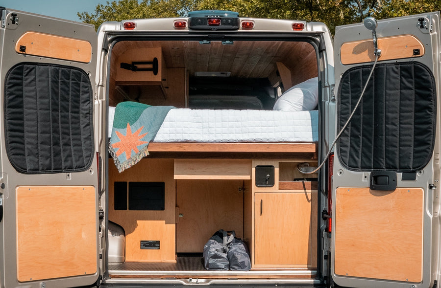 and a compact kitchen.|Inside a beautifully crafted RV rental: A spacious bed