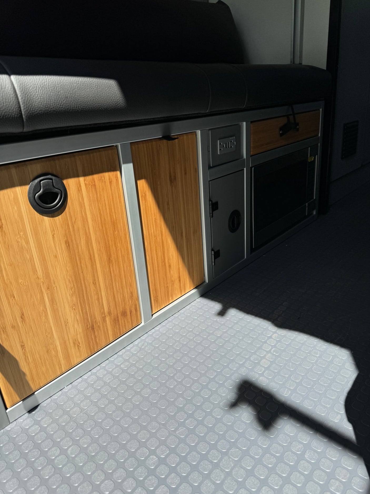 Step inside this RV rental! See the durable gray floor, bamboo cabinets, power outlets, and built-in microwave under a comfy bench.
