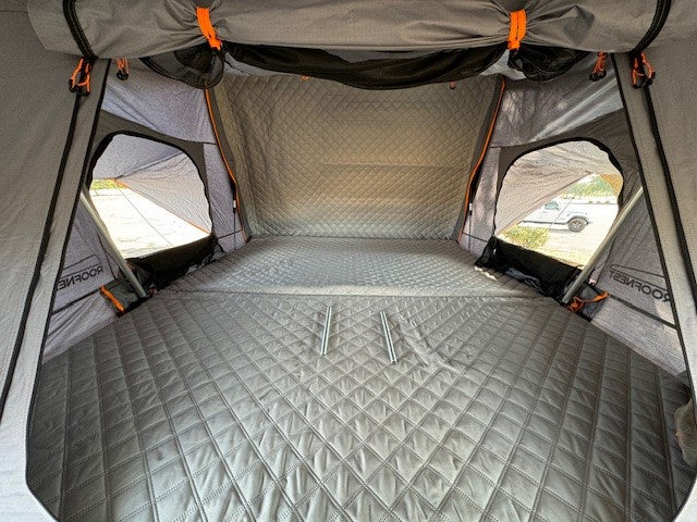 ideal for RV rental. Parked on asphalt lot.|This white RV rental overland trailer with a rooftop tent and large awning setup is ready for camping.|Ready to camp RV rental: White off-road trailer with black rooftop tent & awning deployed in a parking lot.|Relaxing by a campfire at an RV rental campsite. Illuminated camper and people in chairs in a dark forest setting.|Friends gather at a forest camp