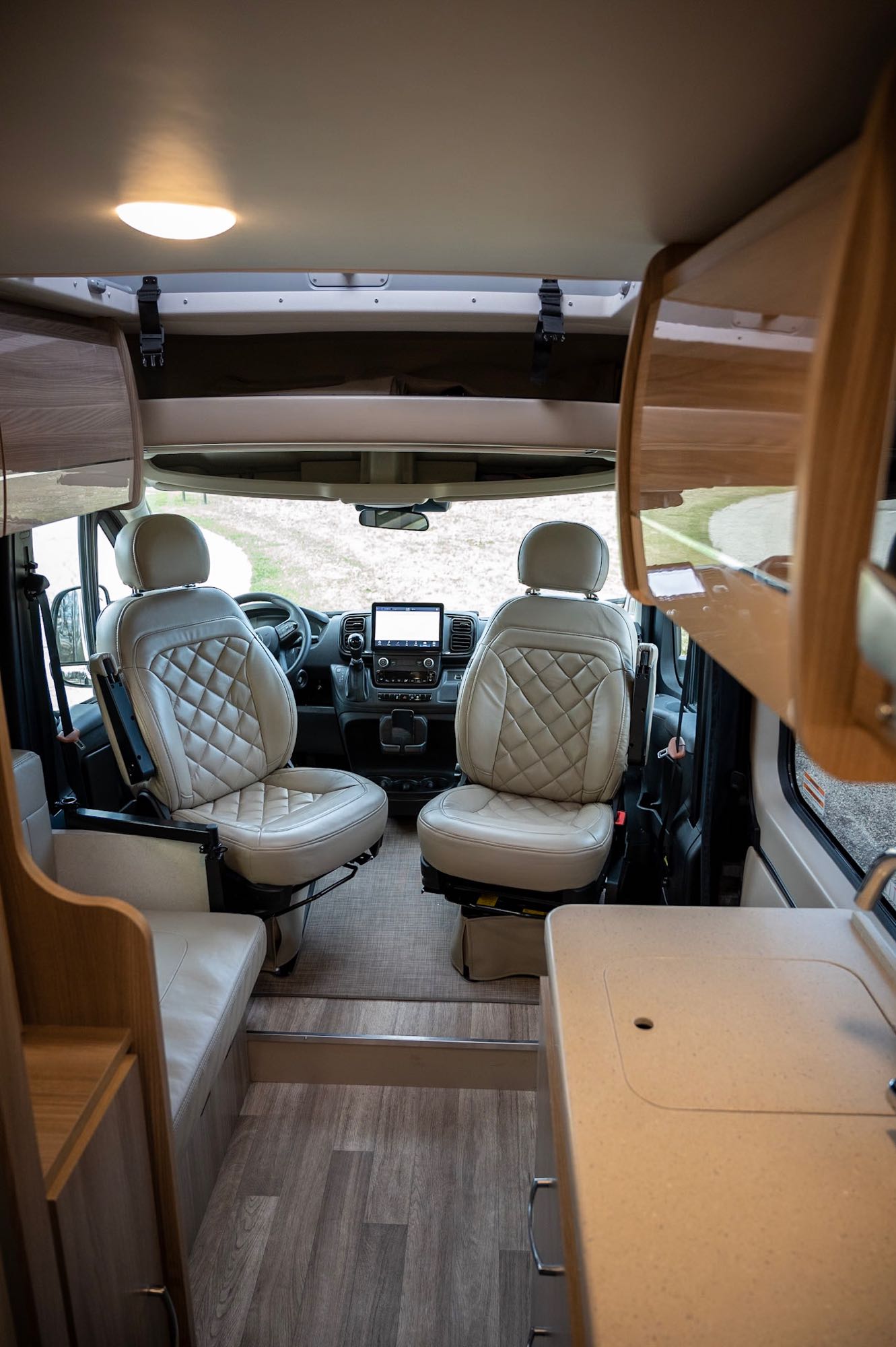 revealing a rooftop.|Inside this RV rental: modern cockpit with tan quilted seats