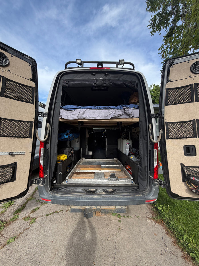 Experience van life with this RV rental: Features a raised bed, organized storage, and a sturdy pull-out platform.