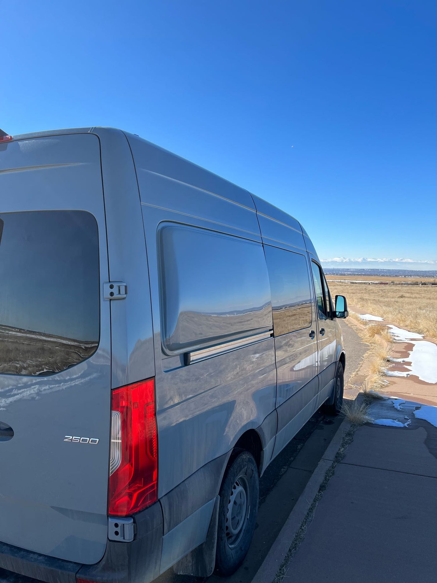 with towering columnar basalt cliffs and lush pine trees under a blue sky.|Gray Mercedes-Benz Sprinter camper van — photo 6