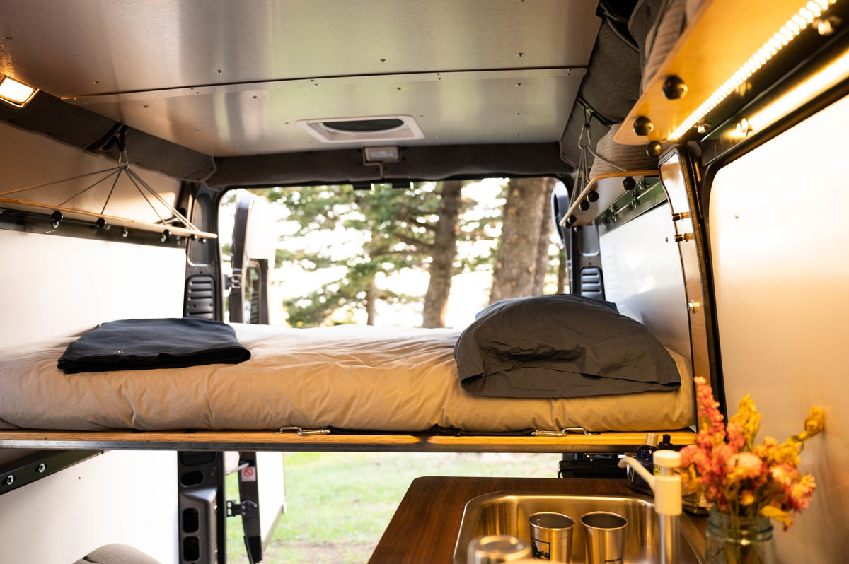 Cozy rv rental camper interior: bed, sink, string lights, and a view of sunlit trees. Ideal for a road trip. — photo 5