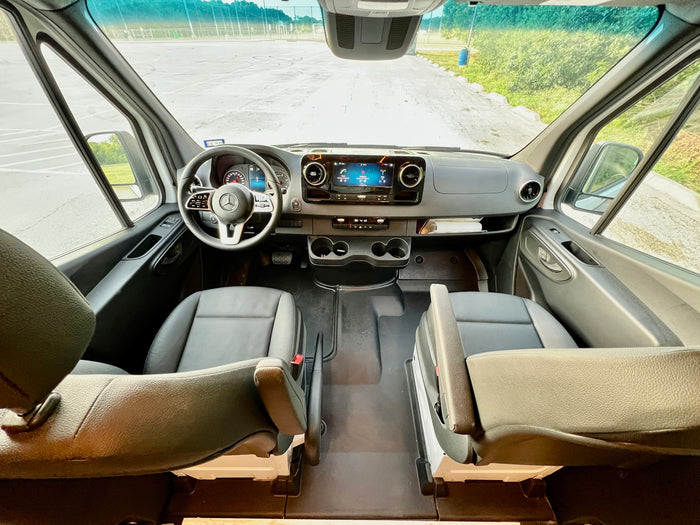 RV rental: The spacious interior of a modern camper van, showcasing the front seats, dashboard, and clear road view.