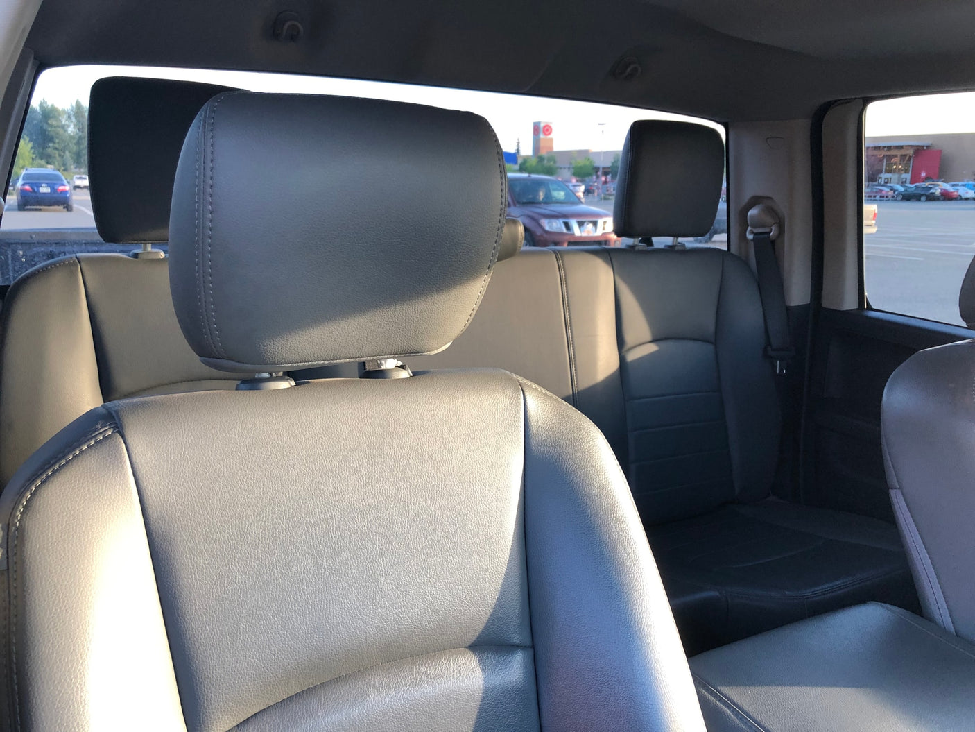and bright parking lot visible through windshield.|Pickup truck in a shopping center parking lot at dusk