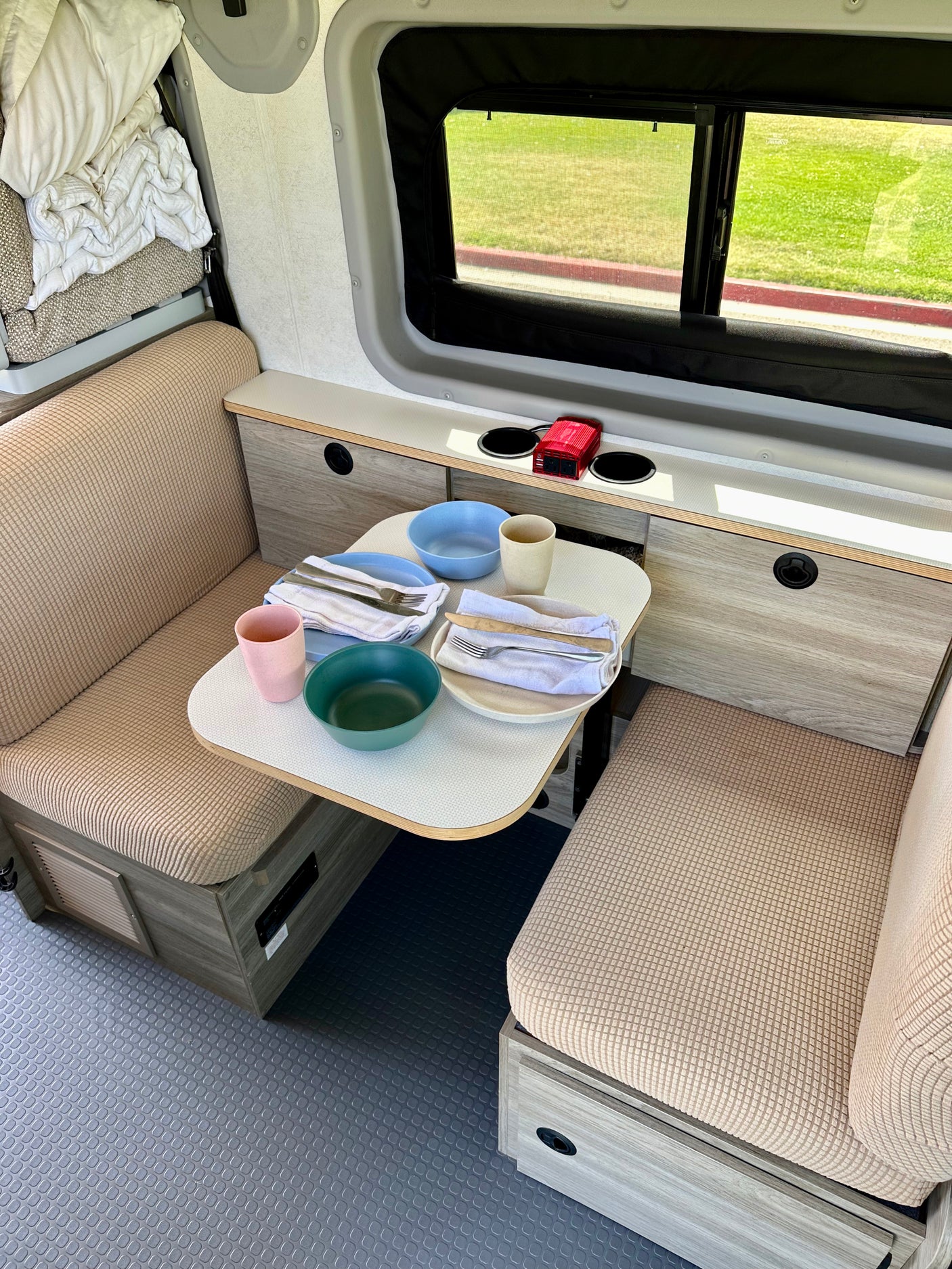 Modern rv rental interior showing a dining nook with set table, benches, and ample storage. Perfect for travel!