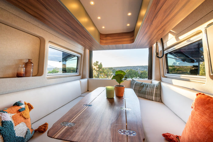 Step into this modern RV rental's cozy interior, featuring a comfortable dining area, stylish decor, and scenic outdoor views.