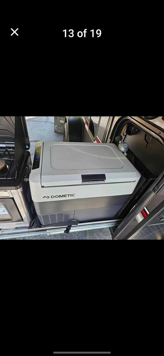 An RV rental's slide-out outdoor kitchen with a Dometic portable fridge/freezer and stove, ready for camping adventures.