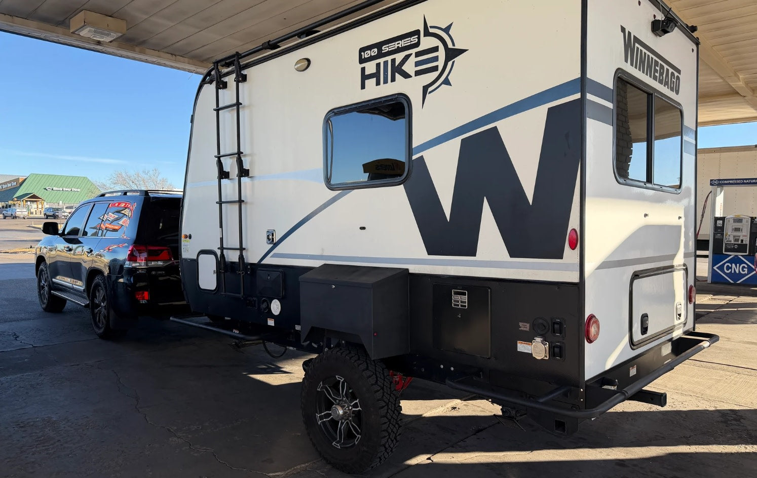 lit under a starry sky. Green and blue lights are visible among the clouds.|A Winnebago Hike RV rental
