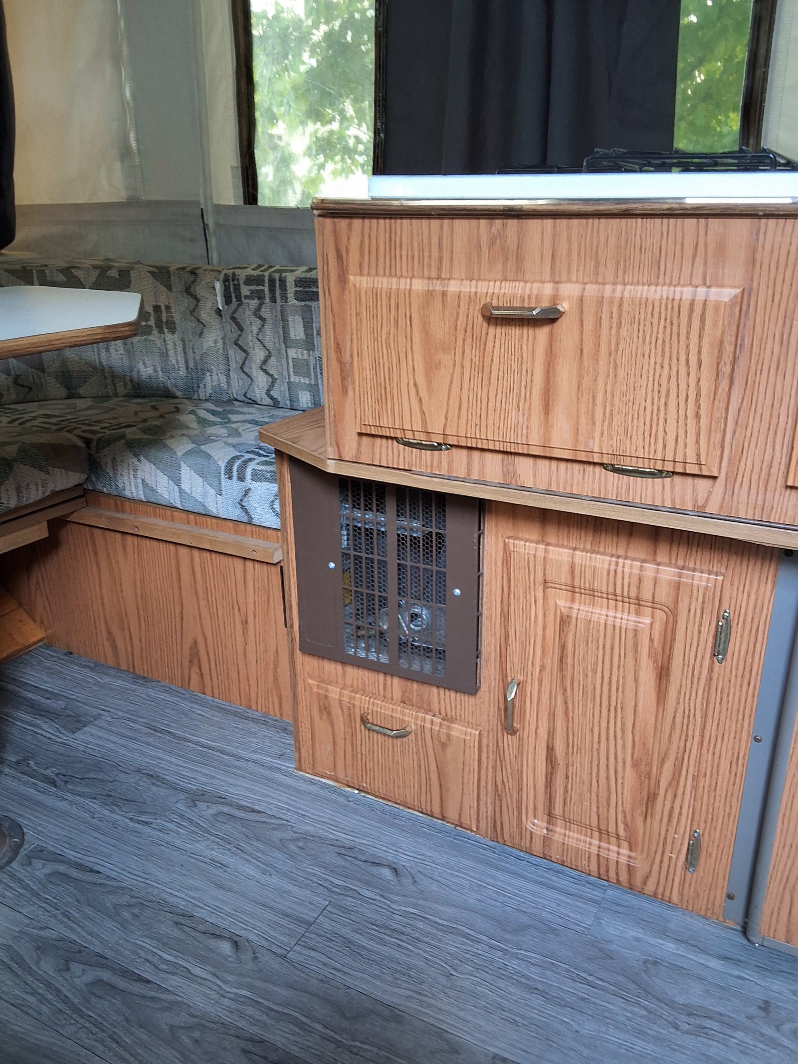 RV rental interior: cozy dinette with patterned cushions, wood-grain cabinets, and kitchen stove.