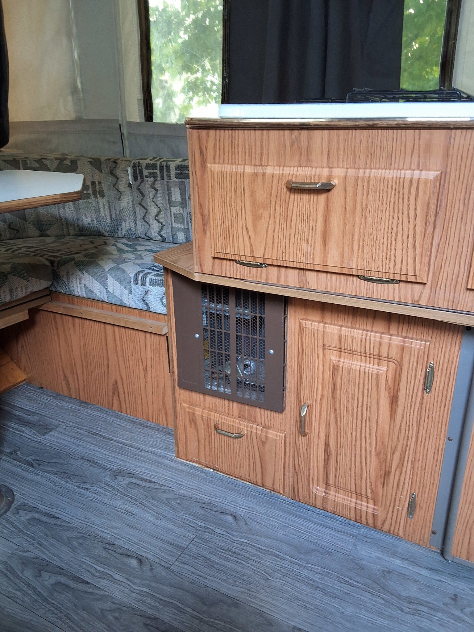 RV rental interior: cozy dinette with patterned cushions, wood-grain cabinets, and kitchen stove.
