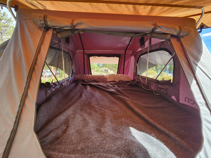 Comfortable rooftop tent interior with bedding visible, great for an RV rental camping adventure.