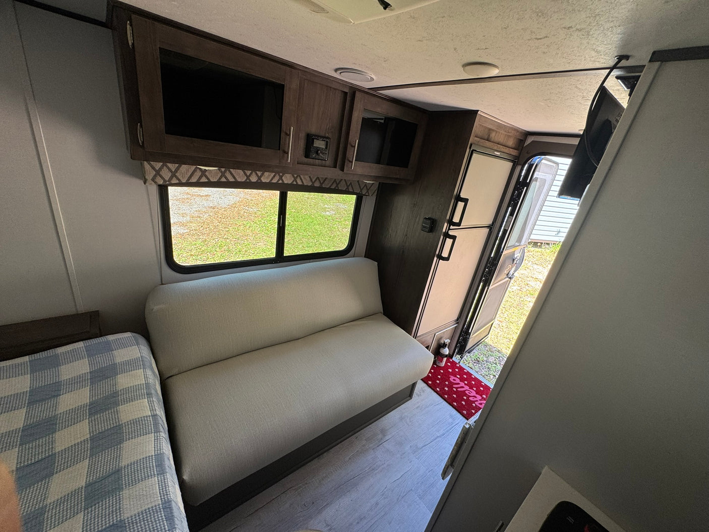 Interior of an rv rental features a cozy bed, sofa, overhead cabinets, and a kitchen area, providing a comfortable camper living space.