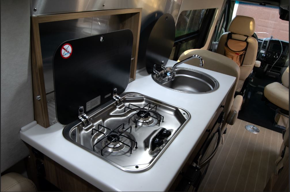and space-saving design.|Cozy RV rental interior with a mounted TV above a cream lounge seat