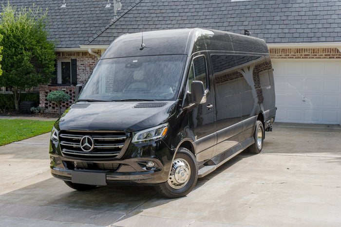 Sleek black Mercedes-Benz Sprinter van in a sunny driveway. Ideal for your next RV rental or luxury group travel adventure.