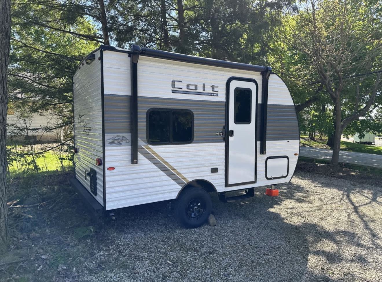 This compact white & grey Colt travel trailer RV rental is parked on gravel