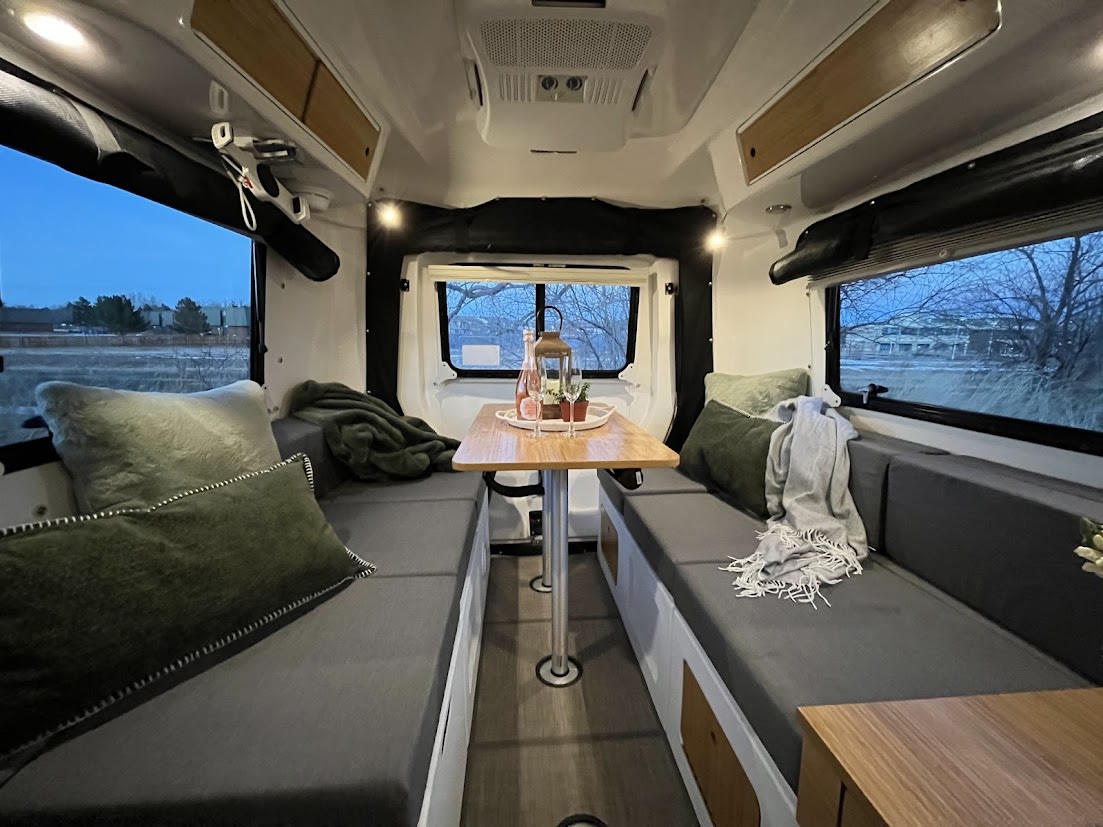 with an evening outdoor view.|This inviting rv rental interior features a grey sofa with green pillows